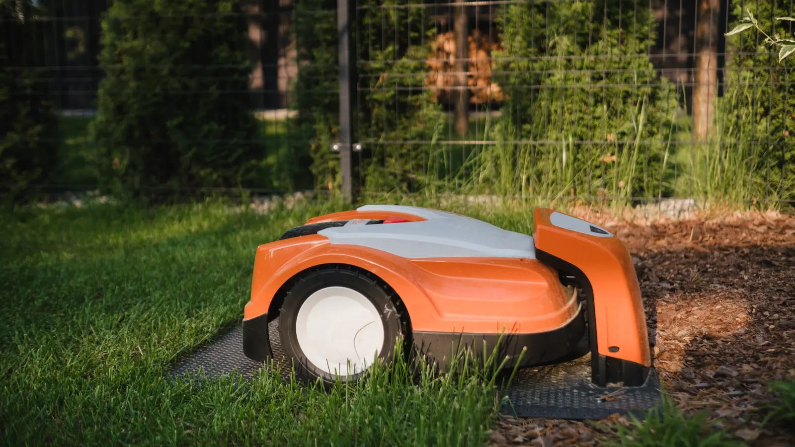 Robot tondeuse en charge sur sa station dans une cour