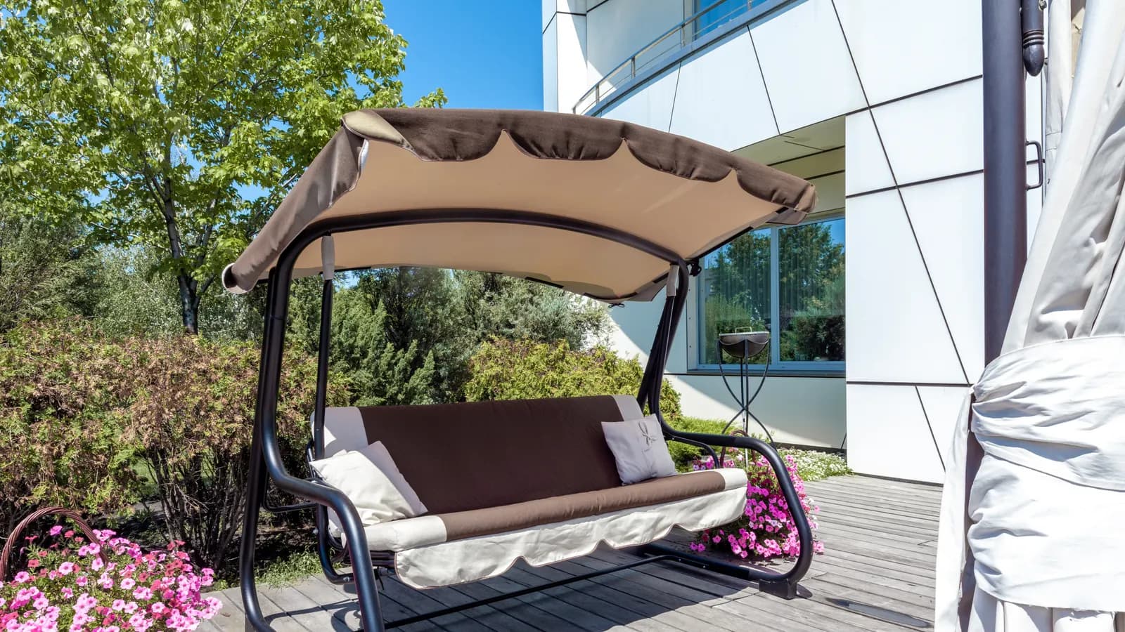 Balancelle de jardin trois places avec auvent sur une terrasse dallée