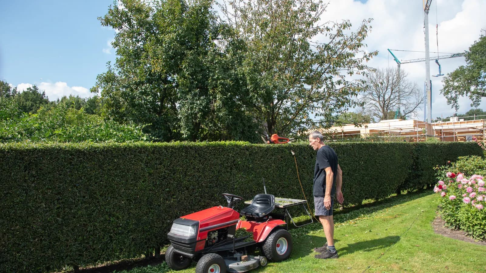 Tracteur tondeuse conduit par un jardinier sur une pelouse