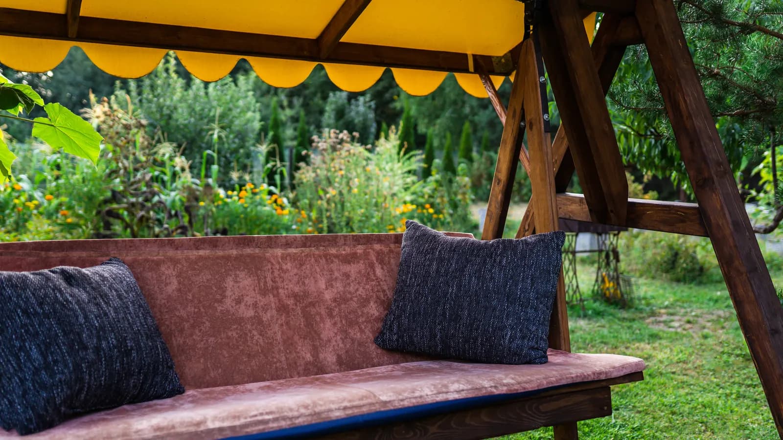 Balancelle de jardin en bois avec auvent près d'une maison