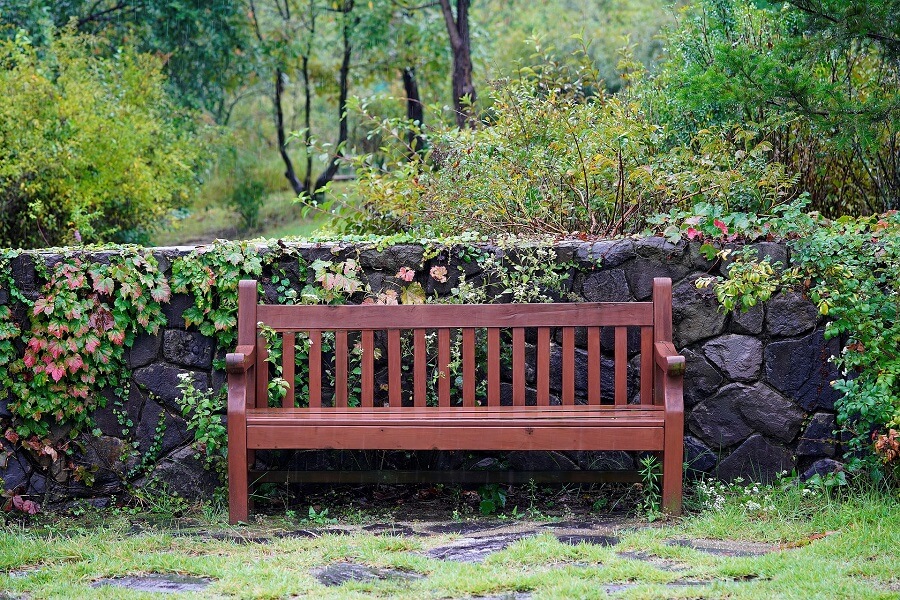 un banc de jardin devant un petit muret
